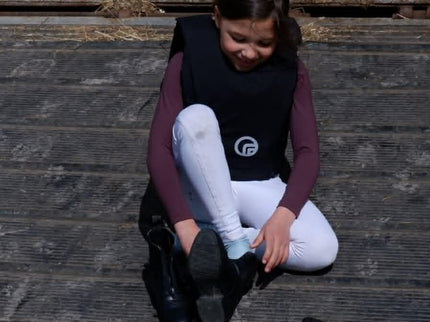 Person sitting on wooden steps with equestrian boots and a saddle pad.