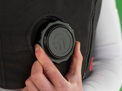 Person adjusting a black body protector with a button on a green background