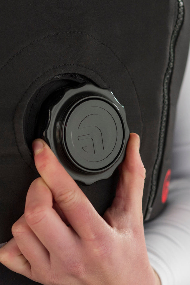 Person adjusting a black body protector with a button on a green background