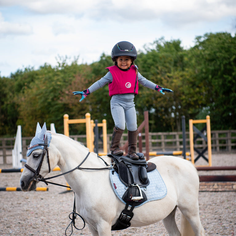 Child riding a white horse in an outdoor equestrian setting