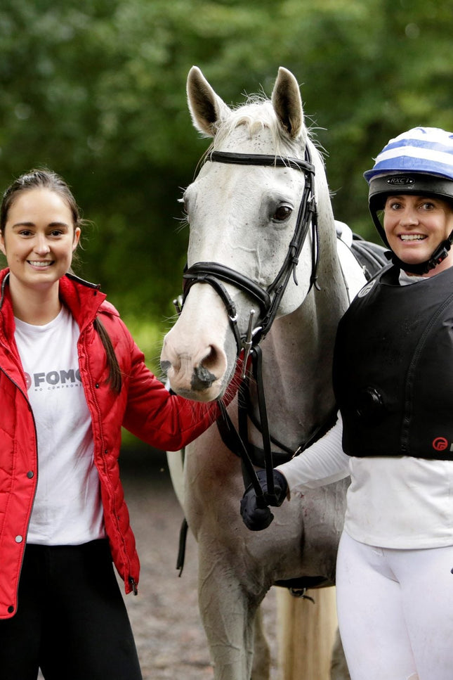 Two women with a horse in an outdoor setting