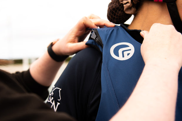 Person adjusting a blue shirt with a logo on a blurred background