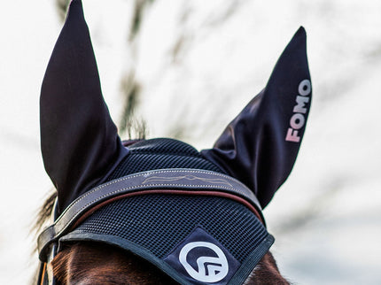 Horse wearing a black fly veil with visible branding, against a blurred natural background.
